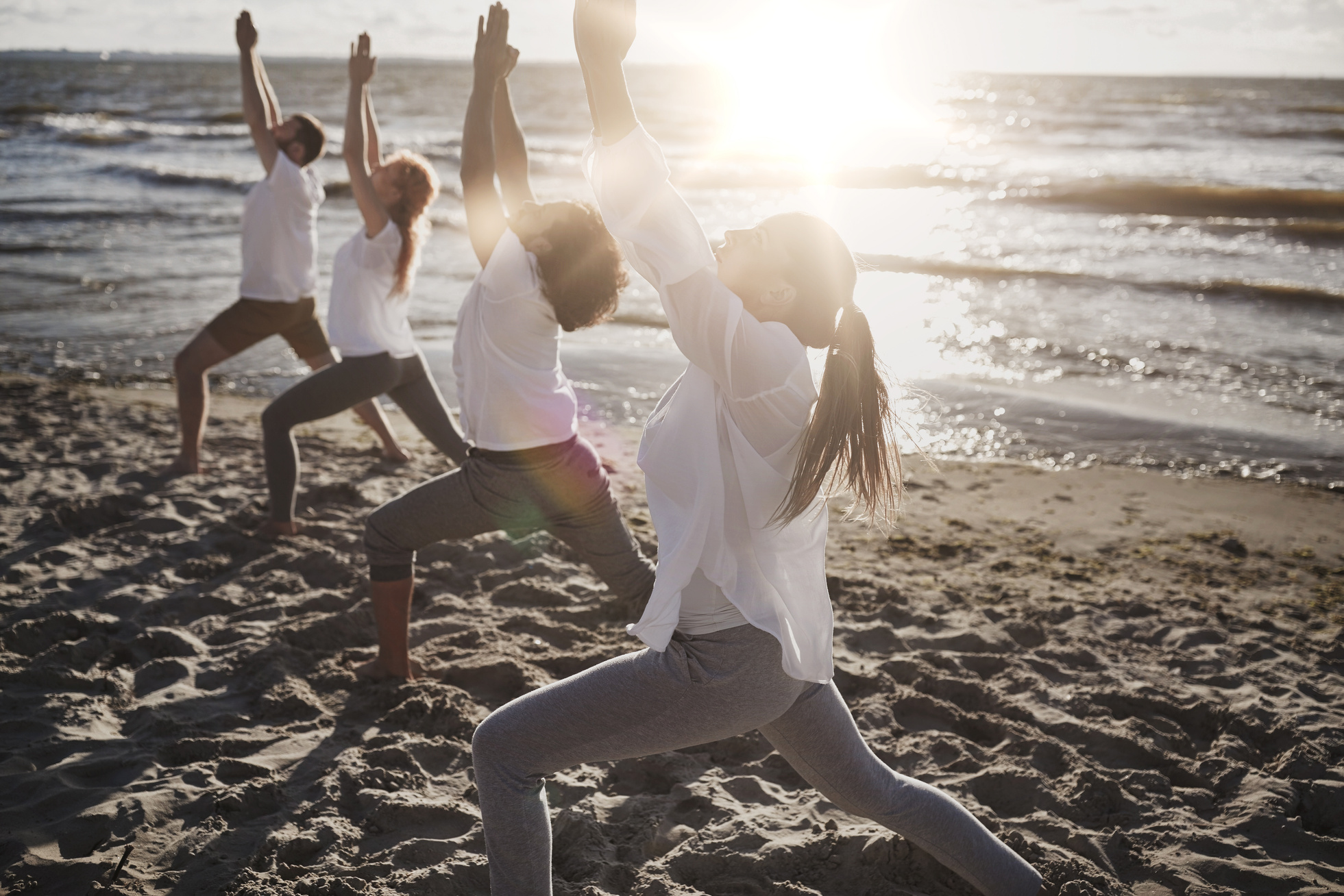 Group of People Making Yoga Exercises on Beach